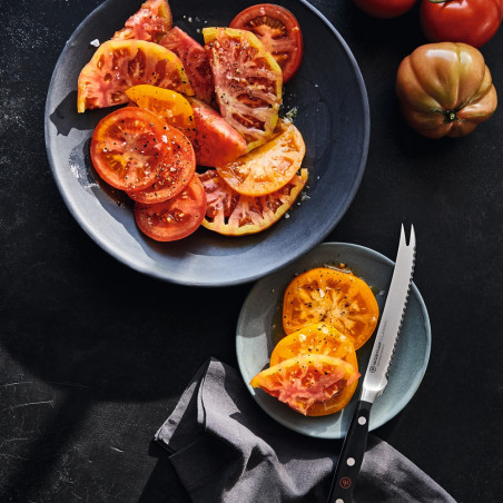Cuchillo para tomate Wüsthof Classic junto a un plato de tomates cortados